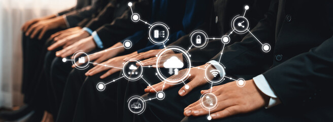 This photo captures business professionals seated in formal attire, showcasing hands in front of digital technology icons, symbolizing modern connectivity and cloud computing innovation. Amity