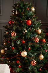 Close-up view of a beautifully decorated Christmas tree with red and gold ornaments, garlands, and glowing lights.
