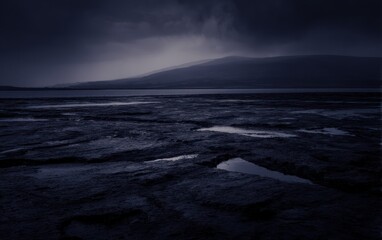 Fototapeta premium Dramatic landscape view with water and mountains under a cloudy overcast sky