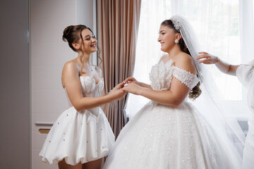Bride and friend share a joyful moment before the wedding ceremony in elegant attire