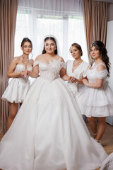 Naklejka premium Bridal preparation with friends in a bright room before the wedding ceremony