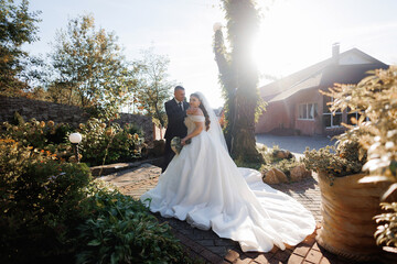 Beautiful outdoor wedding couple poses in sunlight with vibrant flowers and greenery