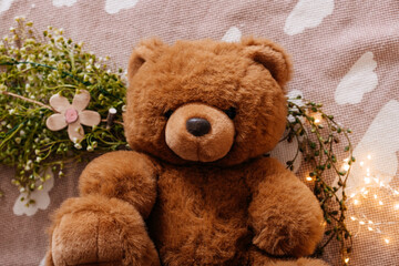 Fluffy Brown Teddy Bear with Floral Décor and Warm Cozy Background Lights