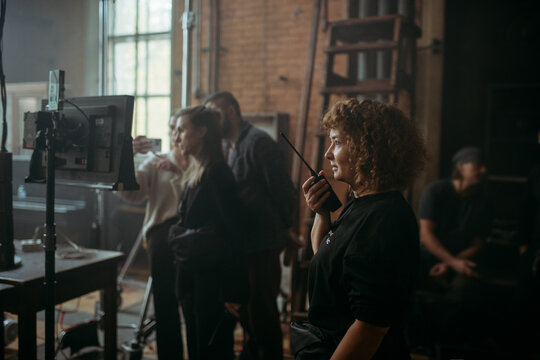 Director at work on the set. The director works with a group or with a playback while filming a movie, advertising, or a TV series. Shooting shift, equipment and group. Modern photography technique.