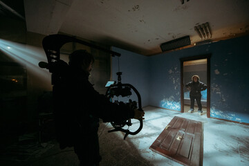 Director of photography with a camera in his hands on the set. Professional videographer at work on filming a movie, commercial or TV series. Filming process indoors, studio