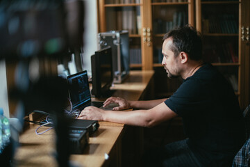 Editing director behind monitors on the set. A video editor edits video online while filming for a playback. Shooting shift, equipment and group. Modern photography technique.