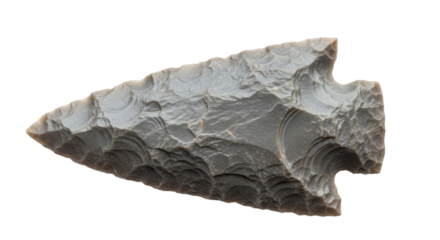 Close-up of a gray stone arrowhead, showcasing intricate flaking and sharp edges.