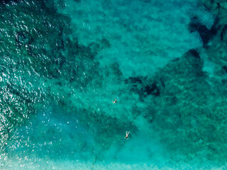 Swimmers in the sea, aerial drone view. Tourists diving and swimming in the water, view from above. Transparent sea water in bay. Summer vacation.