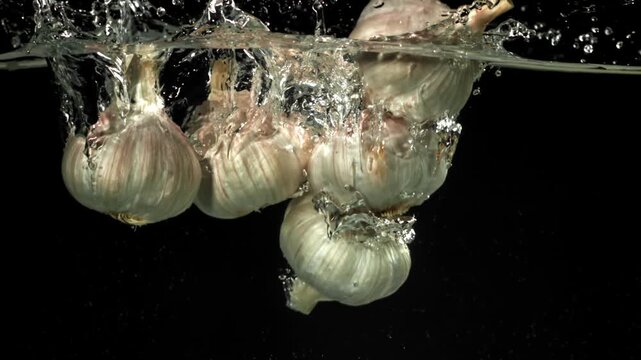 The heads of fresh garlic fall under the water. Filmed on a high-speed camera at 1000 fps. High quality FullHD footage