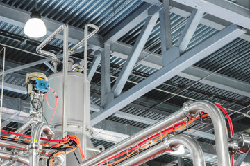 Stainless steel pipes attached to stainless steel tank with industrial food production machine, industrial concept background.