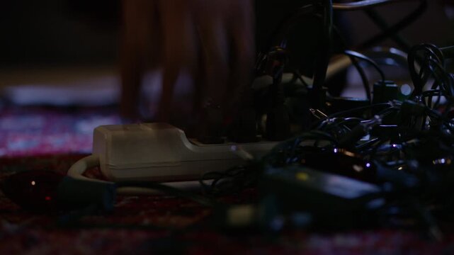 Close-up of someone turning on a power strip with multiple strings of Christmas lights plugged in.
