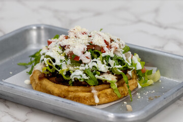 Mouth watering Asada Sope meal overloaded with meat, cheese, and lettuce on a tortilla