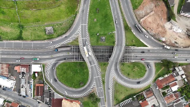 Vista a&eacute;rea de rotat&oacute;ria com tr&aacute;fego intenso em diferentes n&iacute;veis, mostrando organiza&ccedil;&atilde;o vi&aacute;ria, fluxo constante de ve&iacute;culos e infraestrutura urbana moderna em regi&atilde;o urbana movimentada
