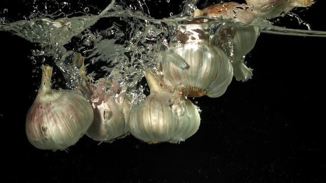 The heads of fresh garlic fall under the water. Filmed on a high-speed camera at 1000 fps. High quality FullHD footage