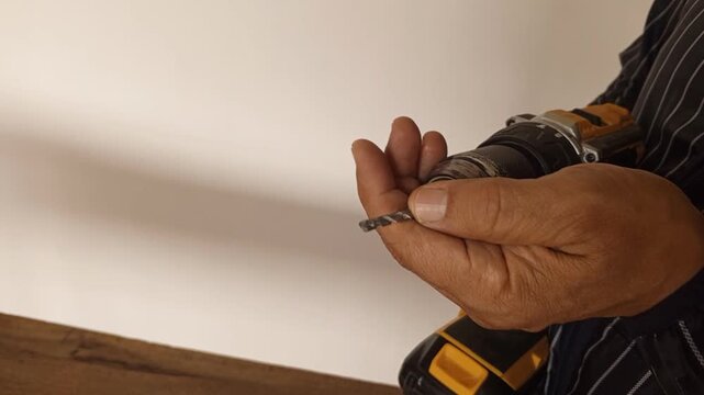 Man inserts the drill bit into a cordless electric drill