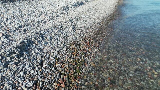 Low-altitude flight over a pebble beach with small waves - Survol &agrave; basse altitude d'une plage de galet avec des vaguelettes