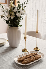 Comfortable table setting with flowers, Inviting cozy dining scene with candles and cookies