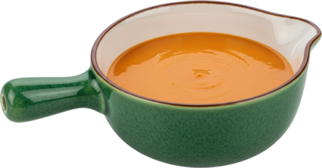 A green ceramic pitcher filled with smooth creamy orange soup featuring a textured exterior and a brown rim isolate food kitchenware liquid hot sauce dip