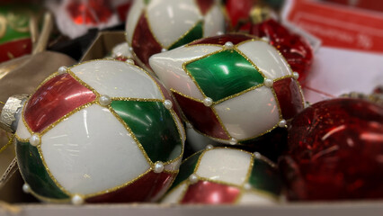 Horizontal defocused mobile photo. Glass toys, bauble, ball with green, white, red circus pattern for Christmas tree on shelf of mass market shop. Concept of Christmas, New Year, eve, gift, sale