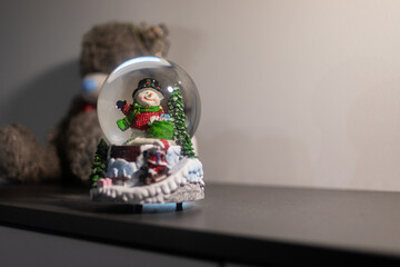 Snow globe with a festive snowman on a shelf, evoking nostalgia, childhood memories, and seasonal gifting. Suitable for holiday marketing, greeting cards, or cozy winter lifestyle content.