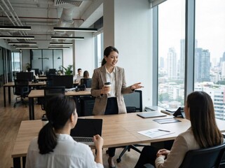 Professional Asian businesswoman presents ideas to colleagues during a collaborative meeting in a modern office.