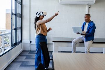 African American coworkers demonstrating VR with white headset and laptop at office table