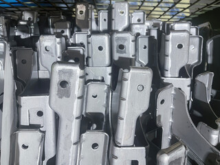 Close-up of mass-produced metal brackets stacked tightly in a bin. The uniform gray color and repetitive industrial shapes symbolize manufacturing, assembly, and construction engineering