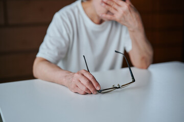 メガネを持ちながら目を押さえるシニア女性