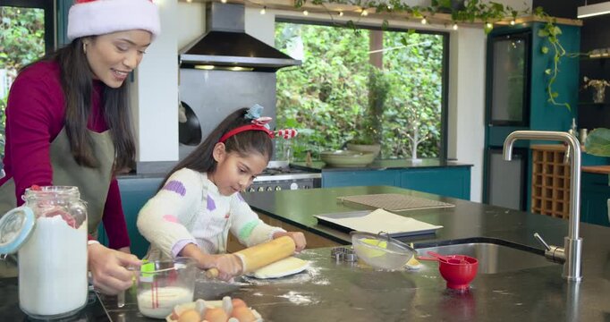 Mom and daughter placing flour jar making dough and cutting shapes for holiday baking in kitchen