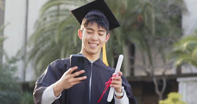 Man holding diploma capturing selfie with phone and scrolling to celebrate graduation on campus