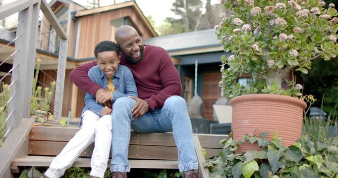 African American father and son hugging tickling on wooden porch steps leaning sparking joy bonding
