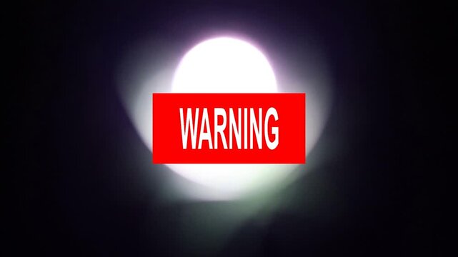 Un primer plano de un rect&aacute;ngulo de color rojo con la palabra advertencia y una luz blanca en movimiento en un fondo negro