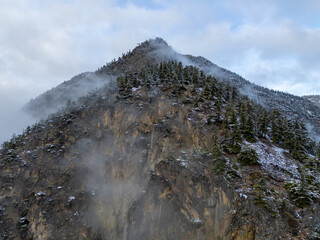 Steep Rocky Mountain Cliff Shrouded in Mist with Sparse Trees in British Columbia