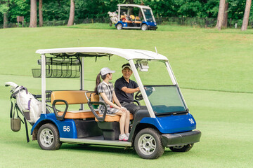 Male and female golfers riding golf carts at a golf course