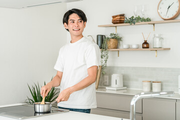 A young Asian man cooking in his home kitchen (cooking boy)
