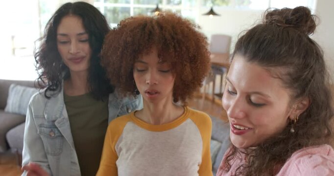 Diverse female friends syncing lip-sync dance after beat drop in bright living room with window