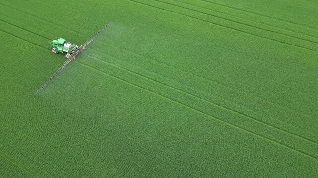 Aerial view of an agricultural machine spreading a product on a field - Vue a&eacute;rienne d'une machine agricole &eacute;pandant un produit phytosanitaire sur un champ
