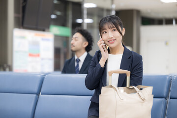 ビジネス女性の電話　空港や駅のターミナルでの出張移動シーン上半身