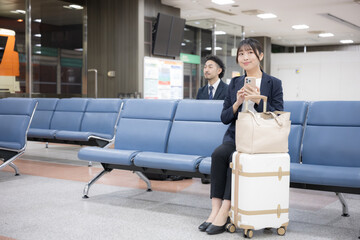 ビジネス女性の電話　空港や駅のターミナルでの出張移動シーン全身の広角