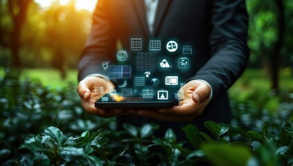 Person in suit holding tablet with glowing digital icons representing renewable energy and sustainability concepts outdoors in natural green environment with sunlight