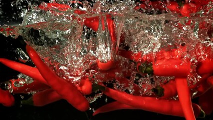 Red chili peppers fall under water. Filmed on a high-speed camera at 1000 fps. High quality FullHD footage - Powered by Adobe