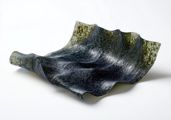 Close-up of a single dark green, textured seaweed sheet with wavy edges lying on a white surface, showcasing its intricate patterns and glossy finish