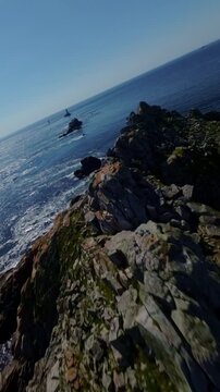 FPV drone races along steep Pointe du Raz cliffs with rugged rock and bright blue sea below