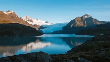 Serene mountain lake reflecting snow-capped peaks under a clear blue sky