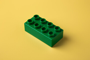 Green lego plastic toy block on yellow background © chee siong teh