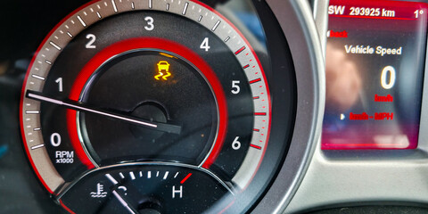 The traction control system warning light on the dashboard when driving on a slippery road. Dangers of driving a car during the winter season.