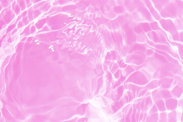 Pink water bubbles on the surface ripples. Defocus blurred transparent pink colored clear calm water surface texture with splash and bubbles. Water waves with shining pattern texture background