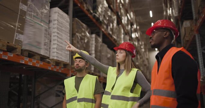 Warehouse team in safety gear navigating inventory in a large storage facility. Dedicated workers collaborating to manage logistics and ensure efficient operations in an industrial environment.