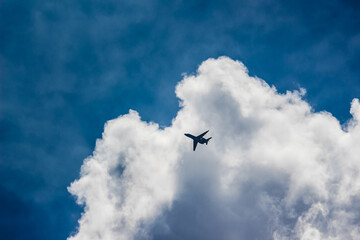 Private jet Emerging From Bright Clouds Against Blue Sky