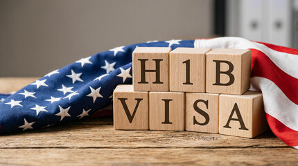 Wooden blocks with H1B visa text on American flag, concept of US work visa, immigration policy and employment sponsorship